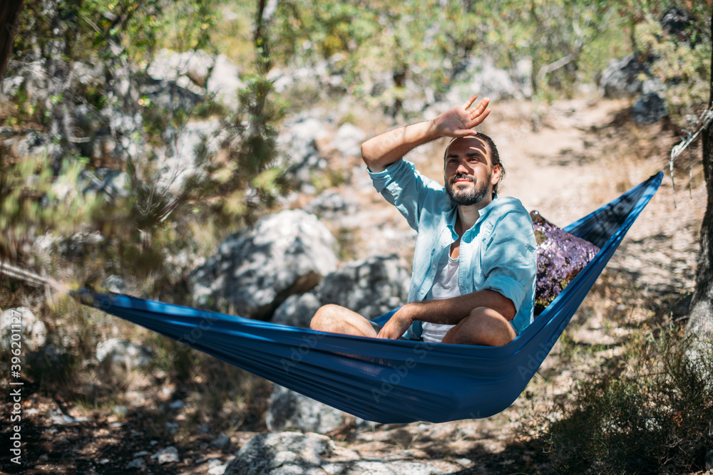 A man in a hammock on a hike in the mountains.