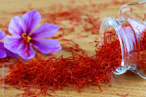 Saffron stigmas scattered on a wooden surface from a glass bottle. Saffron crocus flowers. photo