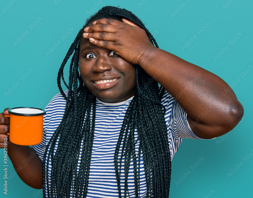 Young black woman with braids drinking a cup coffee stressed and frustrated with hand on head, surprised and angry face