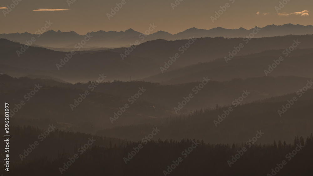 Beautiful sunrise at Ochodzita mountain with a view towards the Beskidy mountains early in cold winter months.