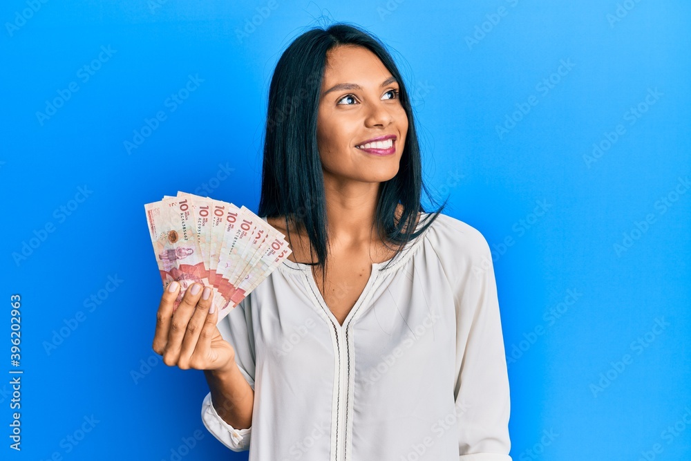 Young african american woman holding 10 colombian pesos banknotes smiling looking to the side and staring away thinking. Young african american woman holding 10 colombian pesos banknotes smiling looking to the side and staring away thinking.
