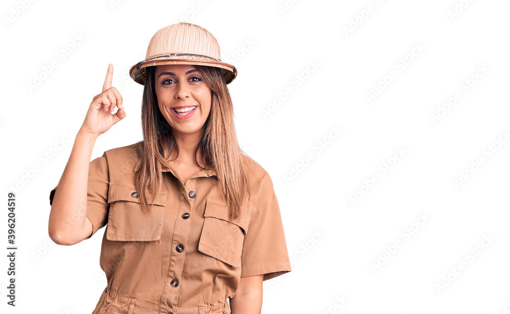 Young beautiful woman wearing explorer hat pointing finger up with successful idea. exited and happy. number one. Young beautiful woman wearing explorer hat pointing finger up with successful idea. exited and happy. number one.