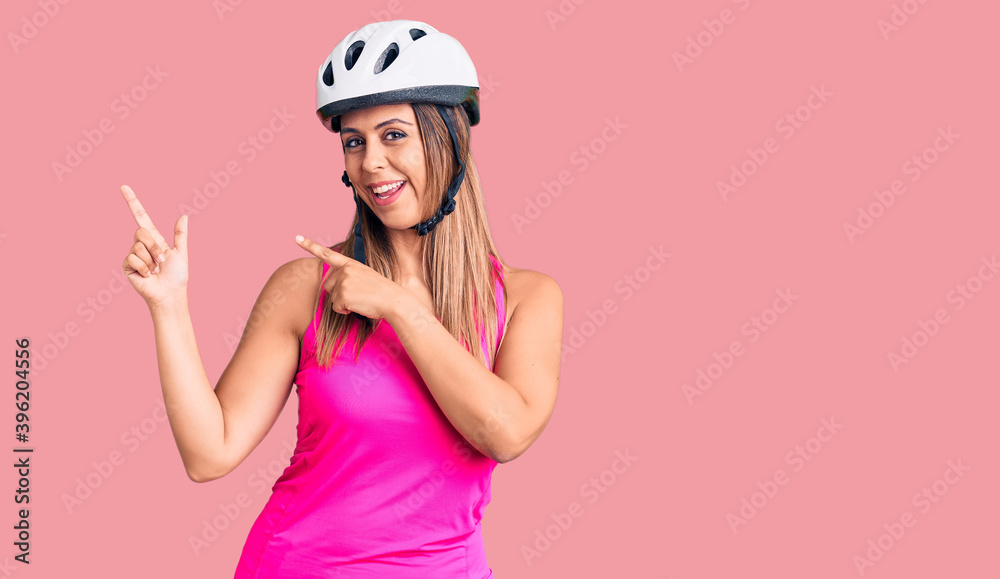 Young beautiful woman wearing bike helmet smiling and looking at the camera pointing with two hands and fingers to the side. Young beautiful woman wearing bike helmet smiling and looking at the camera pointing with two hands and fingers to the side.