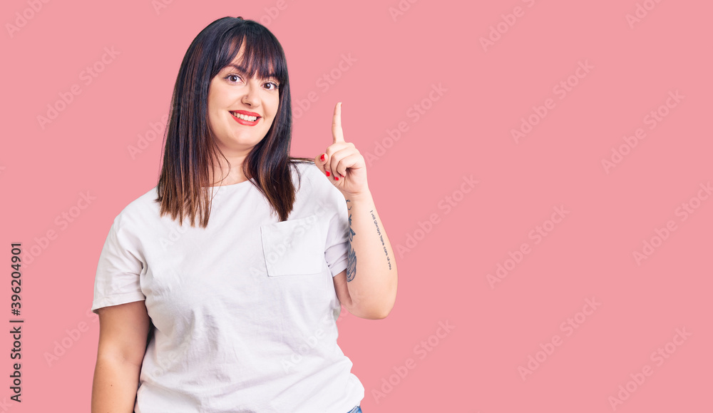 Young plus size woman wearing casual clothes pointing finger up with successful idea. exited and happy. number one. Young plus size woman wearing casual clothes pointing finger up with successful idea. exited and happy. number one.