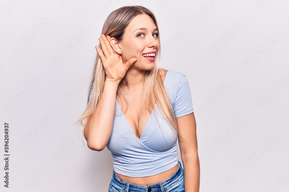 Young blonde woman wearing casual clothes smiling with hand over ear listening and hearing to rumor or gossip. deafness concept. Young blonde woman wearing casual clothes smiling with hand over ear listening and hearing to rumor or gossip. deafness concept.