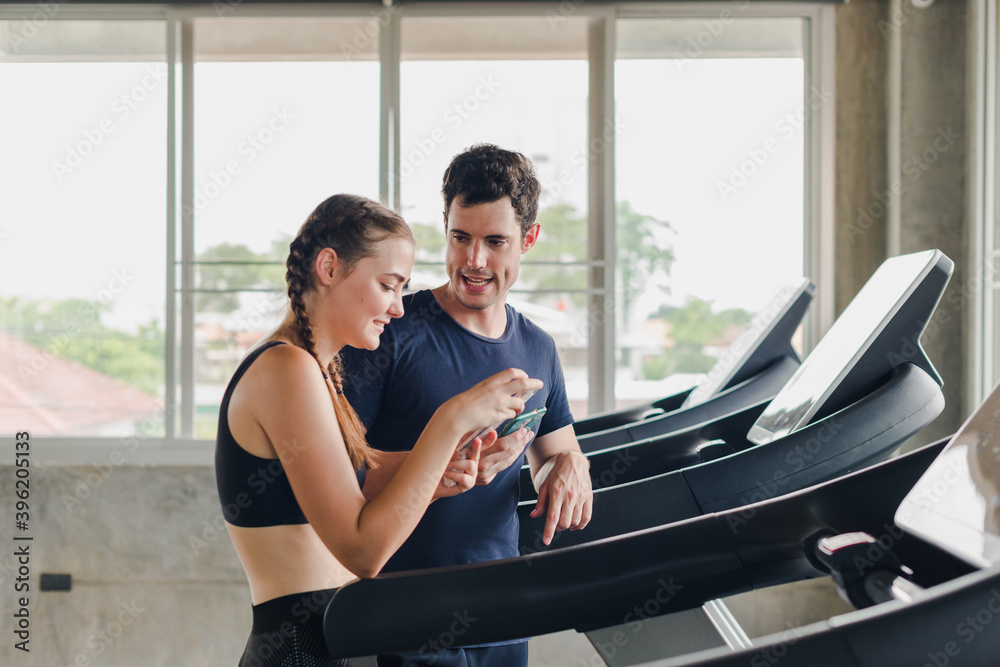 Couples exercise at the gym. Couple having fun playing with smartphones Near the exercise machine