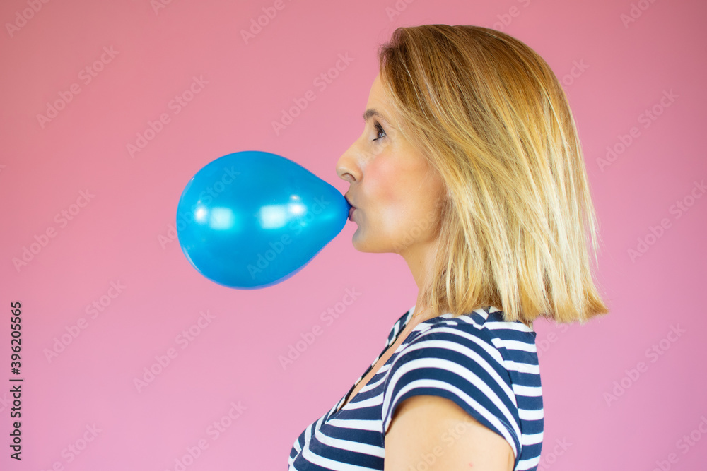 Close up photo of charming nice cute serious focused woman inflating her air ball while isolated with pink background Close up photo of charming nice cute serious focused woman inflating her air ball while isolated with pink background