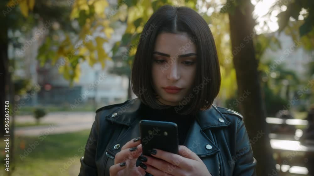 Young unhappy pretty woman wearing a leather jacket is dealing with the phone. Young unhappy pretty woman wearing a leather jacket is dealing with the phone.