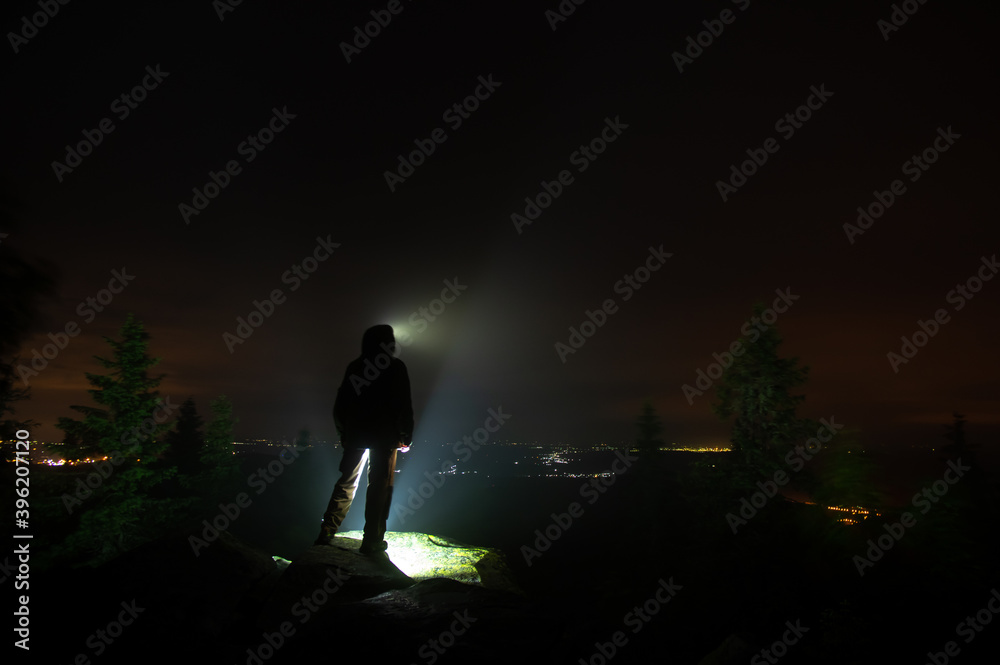 Silhouettes of a man at night in the mountains and village lights