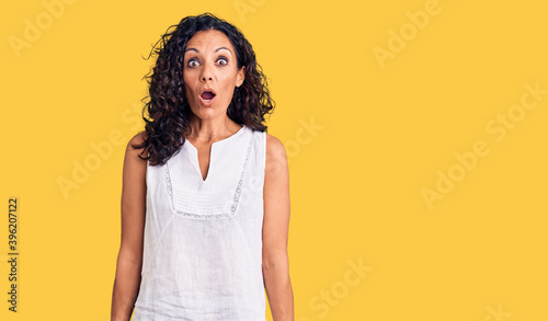 Middle age beautiful woman wearing casual sleeveless t shirt scared and amazed with open mouth for surprise, disbelief face