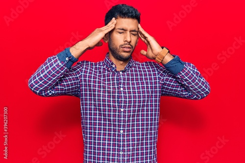 Young latin man wearing casual clothes with hand on head, headache because stress. suffering migraine.