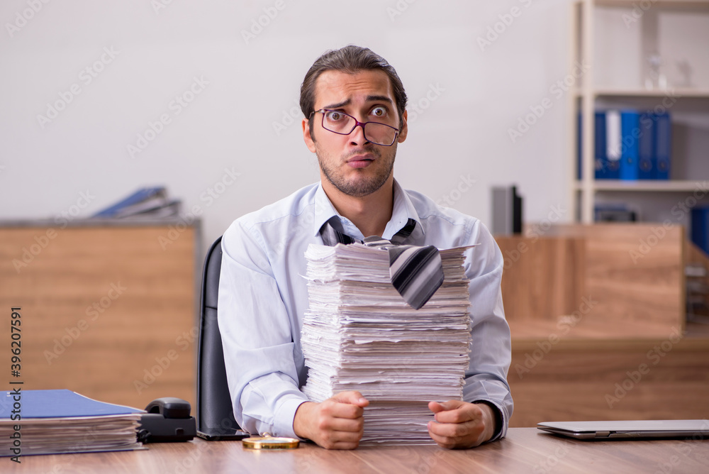 Young male employee unhappy with excessive work in the office
