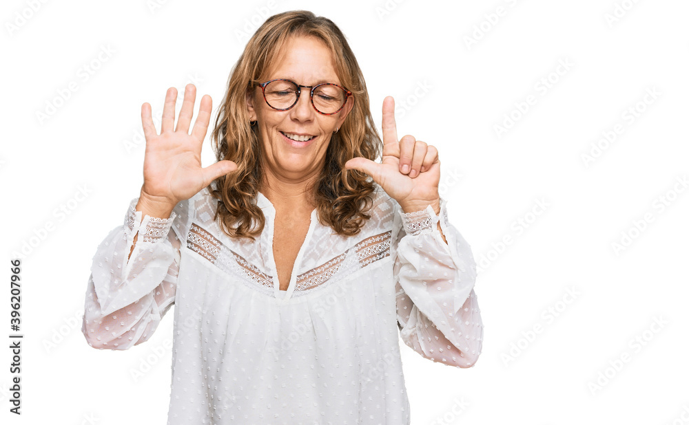 Middle age blonde woman wearing casual white shirt and glasses showing and pointing up with fingers number seven while smiling confident and happy. Middle age blonde woman wearing casual white shirt and glasses showing and pointing up with fingers number seven while smiling confident and happy.