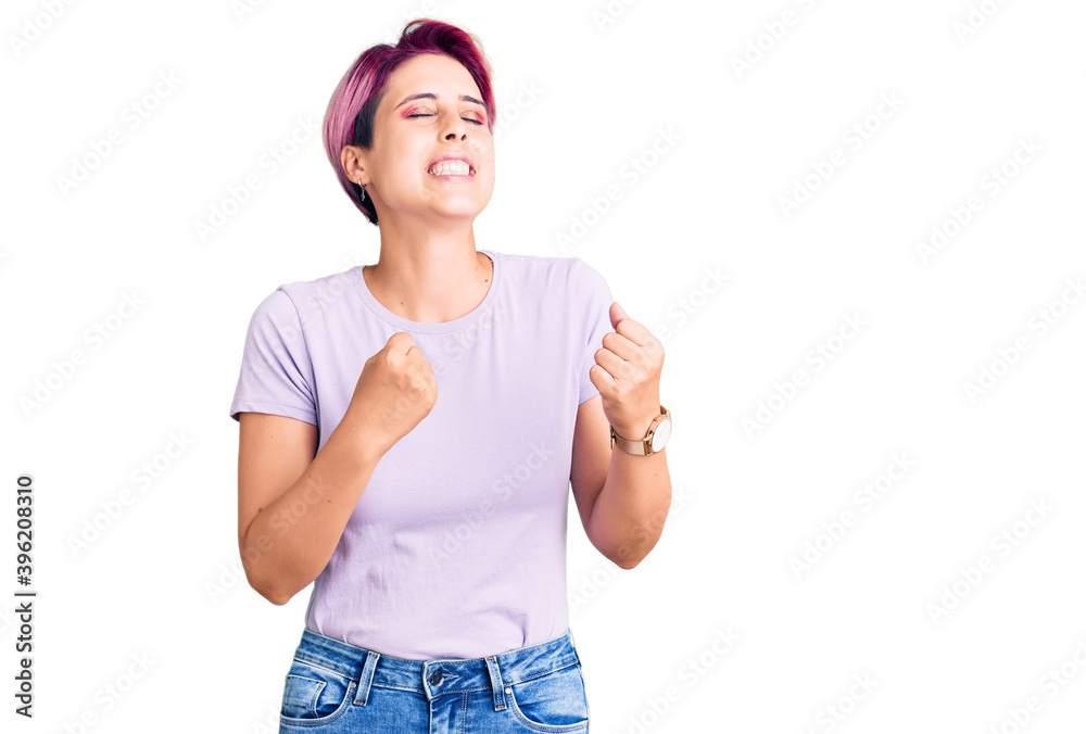 Young beautiful woman with pink hair wearing casual clothes very happy and excited doing winner gesture with arms raised, smiling and screaming for success. celebration concept. Young beautiful woman with pink hair wearing casual clothes very happy and excited doing winner gesture with arms raised, smiling and screaming for success. celebration concept.