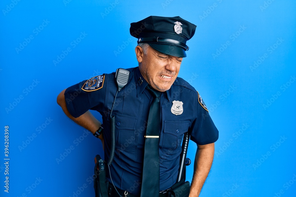 Handsome middle age mature man wearing police uniform suffering of backache, touching back with hand, muscular pain Handsome middle age mature man wearing police uniform suffering of backache, touching back with hand, muscular pain