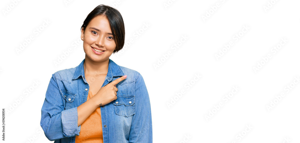 Young beautiful hispanic woman with short hair wearing casual denim jacket cheerful with a smile on face pointing with hand and finger up to the side with happy and natural expression Young beautiful hispanic woman with short hair wearing casual denim jacket cheerful with a smile on face pointing with hand and finger up to the side with happy and natural expression