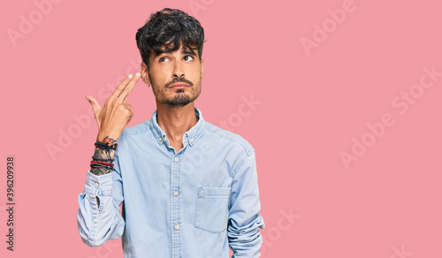 Slika na platnu Young hispanic man wearing casual clothes shooting and killing oneself pointing hand and fingers to head like gun, suicide gesture