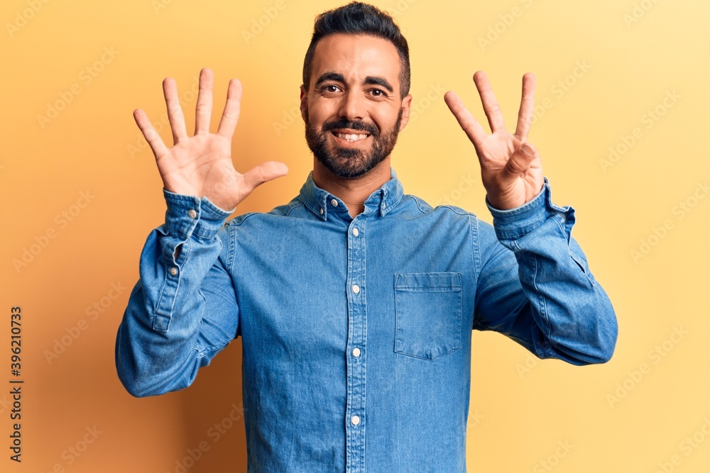 Fototapeta premium Young hispanic man wearing casual clothes showing and pointing up with fingers number eight while smiling confident and happy.
