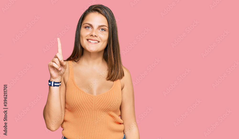 Young caucasian woman wearing casual clothes showing and pointing up with finger number one while smiling confident and happy. Young caucasian woman wearing casual clothes showing and pointing up with finger number one while smiling confident and happy.