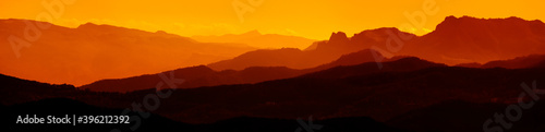 Extra wide panorama of mountain landscape at down. Majestic sunset or sunrise colors over the mountains. Dramatic scene. Beauty world. © Pol Solé