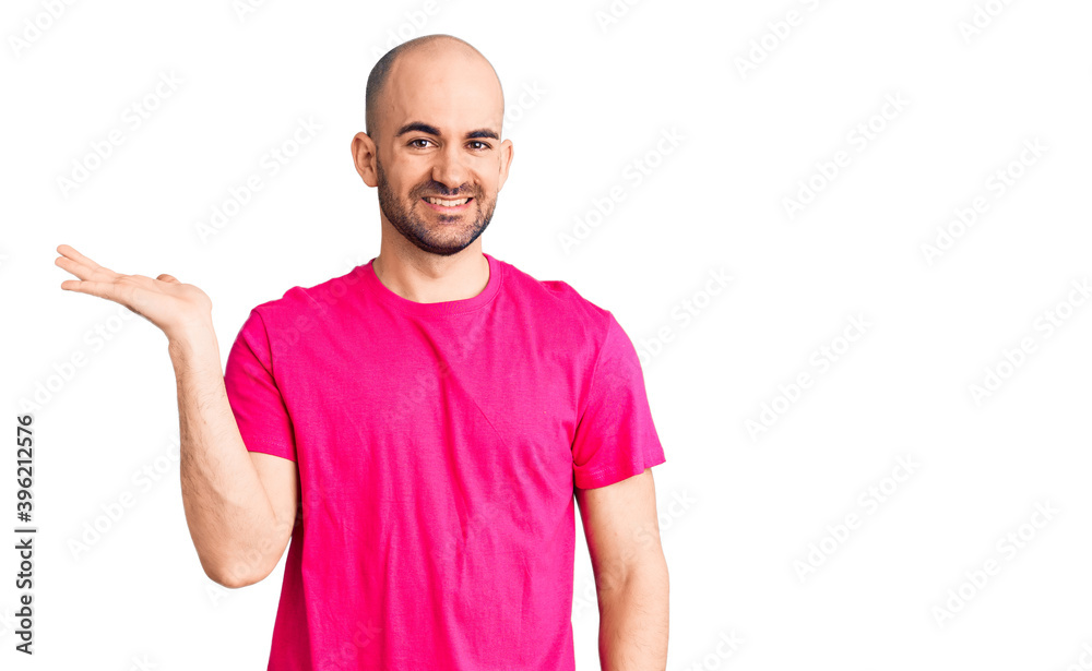 Naklejka premium Young handsome man wearing casual t shirt smiling cheerful presenting and pointing with palm of hand looking at the camera.