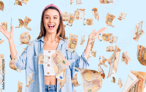 Young beautiful girl wearing casual shirt and diadem celebrating victory with happy smile and winner expression with raised hands photo