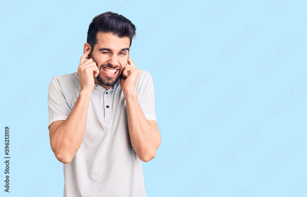 Young handsome man with beard wearing casual polo covering ears with fingers with annoyed expression for the noise of loud music. deaf concept. Young handsome man with beard wearing casual polo covering ears with fingers with annoyed expression for the noise of loud music. deaf concept.
