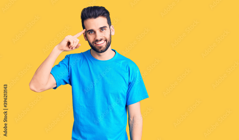 Young handsome man with beard wearing casual t-shirt smiling pointing to head with one finger, great idea or thought, good memory Young handsome man with beard wearing casual t-shirt smiling pointing to head with one finger, great idea or thought, good memory