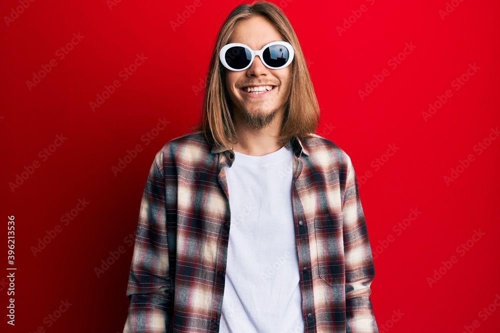 Handsome caucasian man with long hair wearing hipster shirt wearing sunglasses with a happy and cool smile on face. lucky person. Handsome caucasian man with long hair wearing hipster shirt wearing sunglasses with a happy and cool smile on face. lucky person.