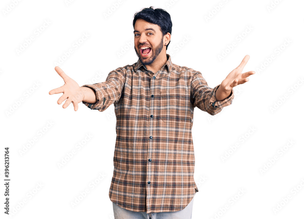 Young hispanic man wearing casual clothes smiling cheerful offering hands giving assistance and acceptance. Young hispanic man wearing casual clothes smiling cheerful offering hands giving assistance and acceptance.