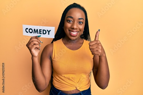 Canvastavla Young african american woman holding comedy word paper smiling happy and positiv