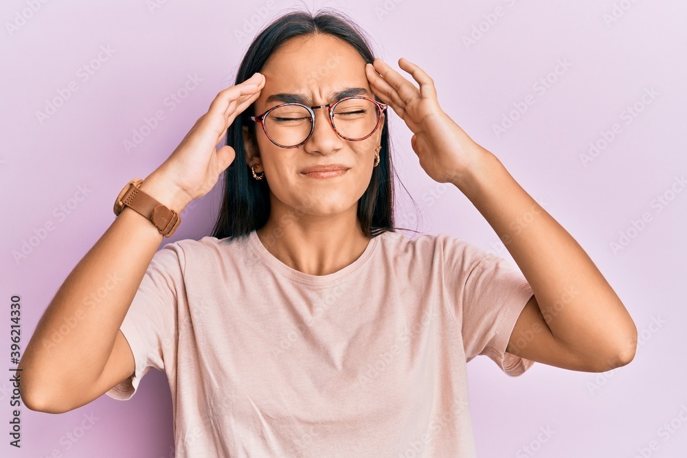 Young asian woman wearing casual clothes and glasses with hand on head, headache because stress. suffering migraine. Young asian woman wearing casual clothes and glasses with hand on head, headache because stress. suffering migraine.