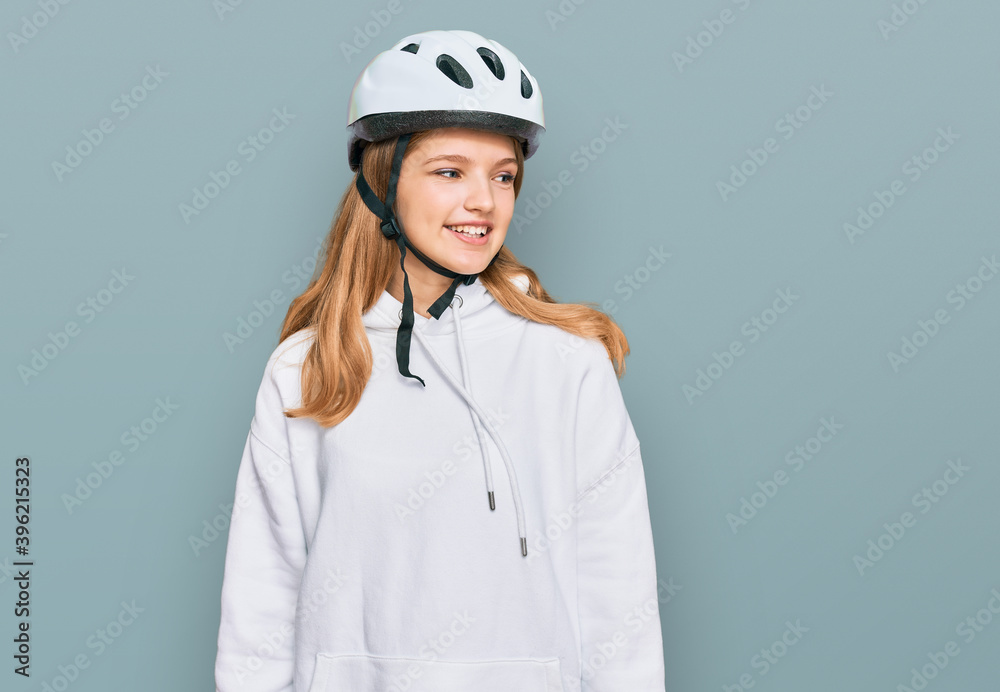 Beautiful young caucasian girl wearing bike helmet looking away to side with smile on face, natural expression. laughing confident. Beautiful young caucasian girl wearing bike helmet looking away to side with smile on face, natural expression. laughing confident.