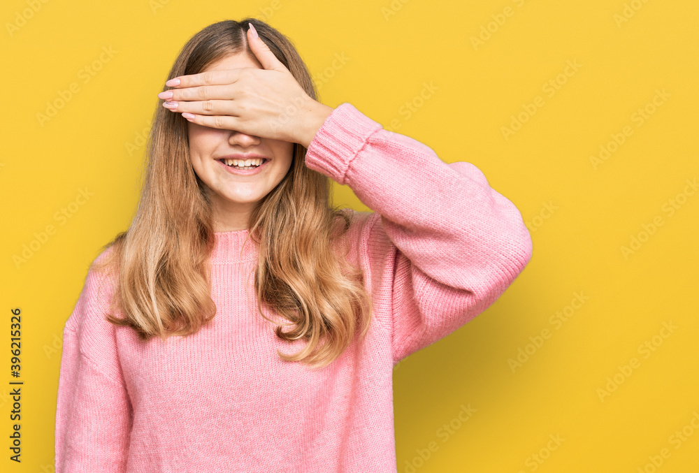 Beautiful young caucasian girl wearing casual winter sweater smiling and laughing with hand on face covering eyes for surprise. blind concept. Beautiful young caucasian girl wearing casual winter sweater smiling and laughing with hand on face covering eyes for surprise. blind concept.