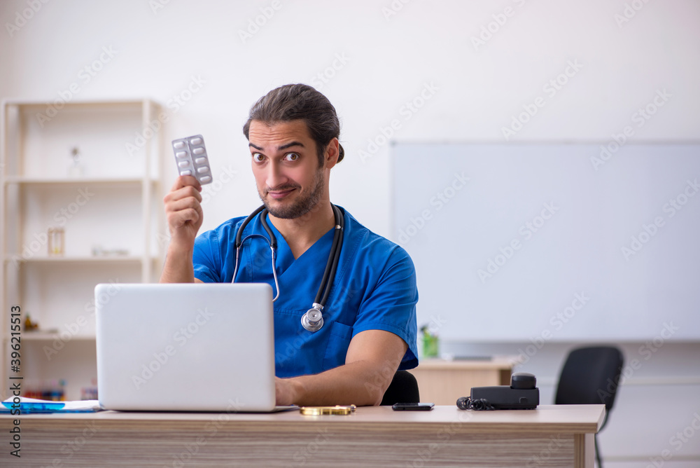 Young male doctor suggesting pills in the clinic Young male doctor suggesting pills in the clinic
