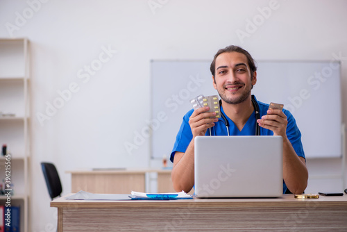 Young male doctor suggesting pills in the clinic