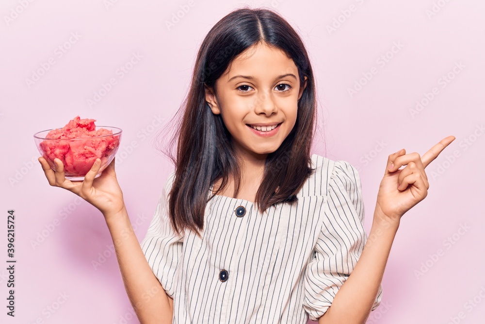 Beautiful child girl holding ice cream smiling happy pointing with hand and finger to the side Beautiful child girl holding ice cream smiling happy pointing with hand and finger to the side