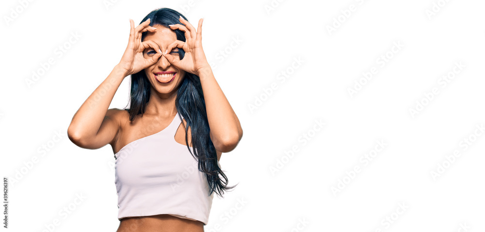 Beautiful hispanic woman wearing casual clothes doing ok gesture like binoculars sticking tongue out, eyes looking through fingers. crazy expression. Beautiful hispanic woman wearing casual clothes doing ok gesture like binoculars sticking tongue out, eyes looking through fingers. crazy expression.