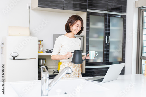 キッチンでパソコンを見る女性 お茶