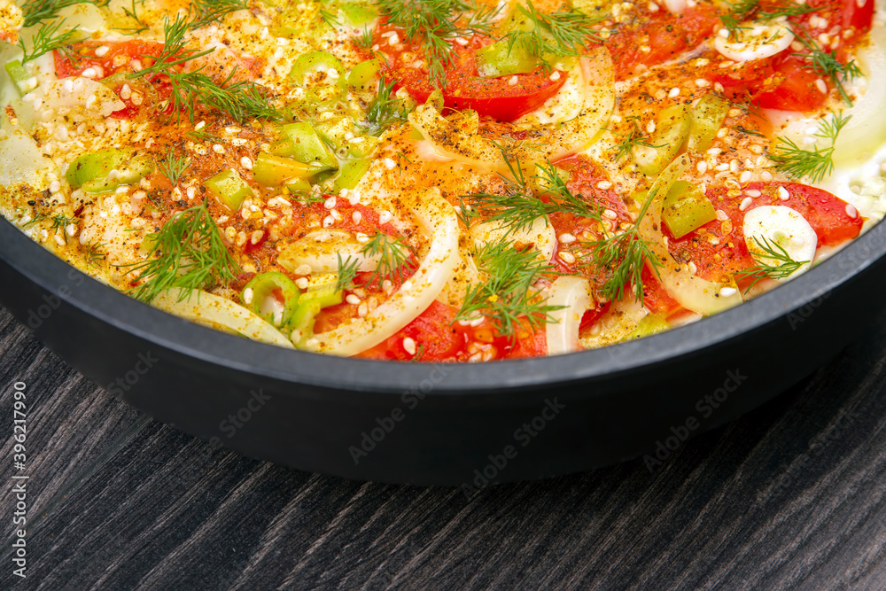 cooked fried omelet with herbs, spices and vegetables in a black pan on a wooden table cooked fried omelet with herbs, spices and vegetables in a black pan on a wooden table