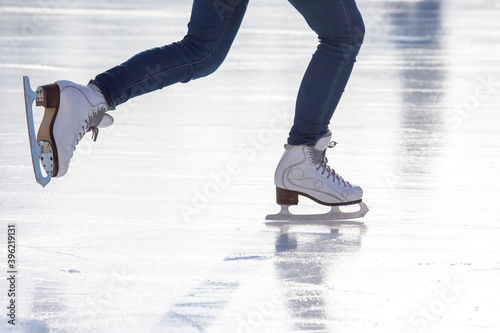 legs of a woman in blue jeans and white skates on an ice rink. hobbies and leisure. winter sports