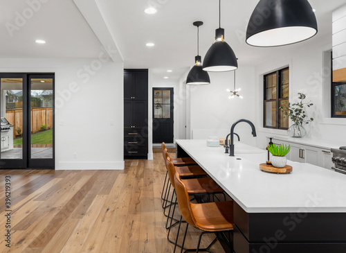 Beautiful kitchen in new home. Luxury farmhouse style home with open floor plan. Features large island, farmhouse sink, hardwood floors, and sliding glass doors to covered patio.