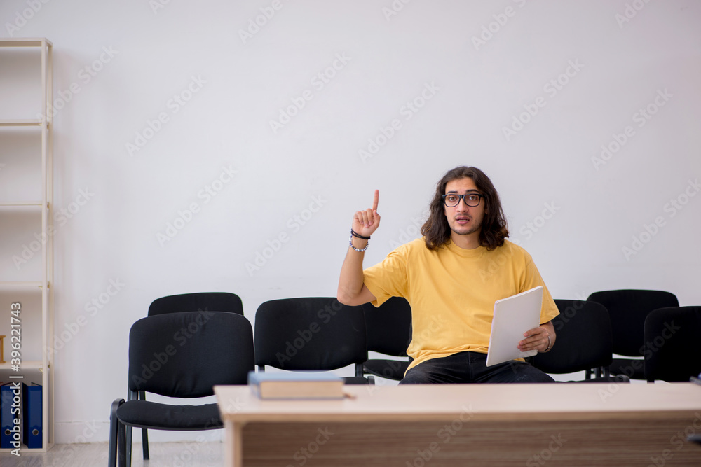 Young male student waiting for teacher in the classroom Young male student waiting for teacher in the classroom