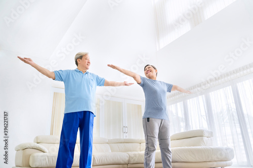 Happy old couple exercising together in living room