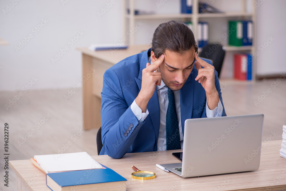 Young male employee and too much work in the office Young male employee and too much work in the office