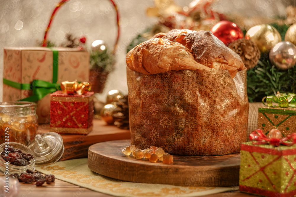 Fototapeta premium Panettone, raisins and candied fruit cubes on wooden cutting board with christmas ornaments