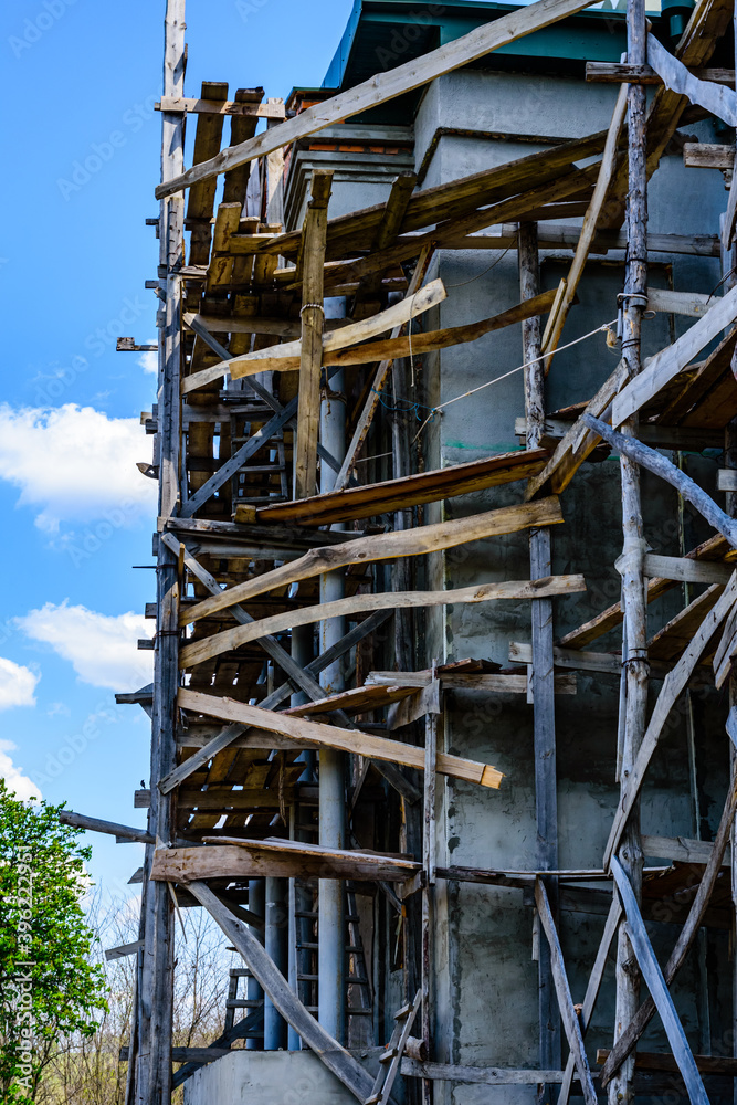 Wooden scaffolding near the old building. Ancient building restoration