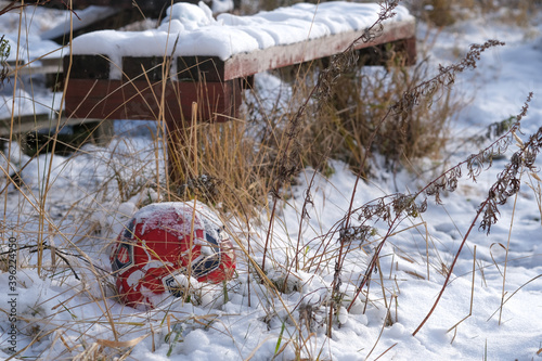 Soccer ball in frozen grass with snow..Bench in the snow.