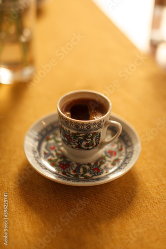 turkish coffee in decorative eastern cup on orange tablecloth  detail selective focus vertical shot