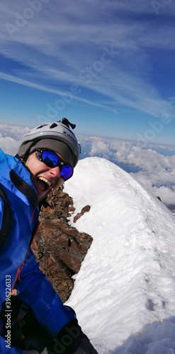 Alpinista che urla e sorride felice ed euforico in cima alla montagna con neve e cielo blu assolato nelle alpi-Monte Rosa photo